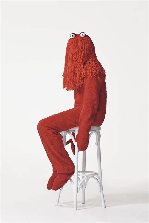 A Person Sitting On Top Of A White Stool Wearing An Orange Suit And Red