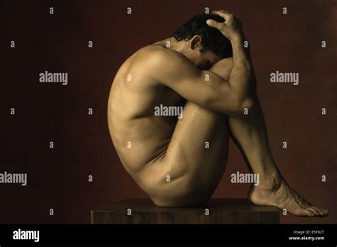 Nude Man Sitting In Fetal Position Hands On Head Side View Stock
