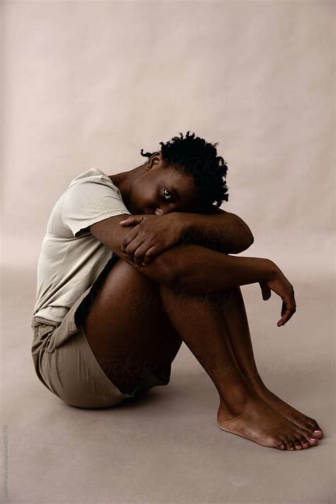 Barefoot Black Female Embracing Knees By Stocksy Contributor Danil