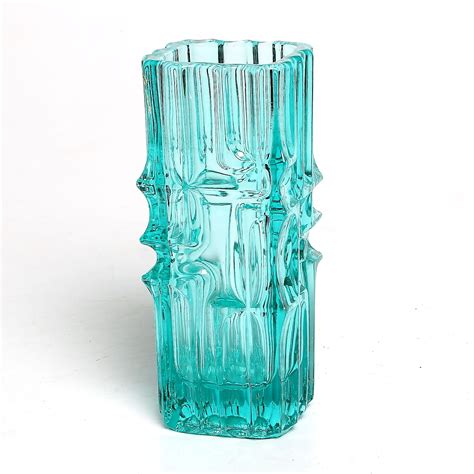 A Green Glass Vase Sitting On Top Of A White Table