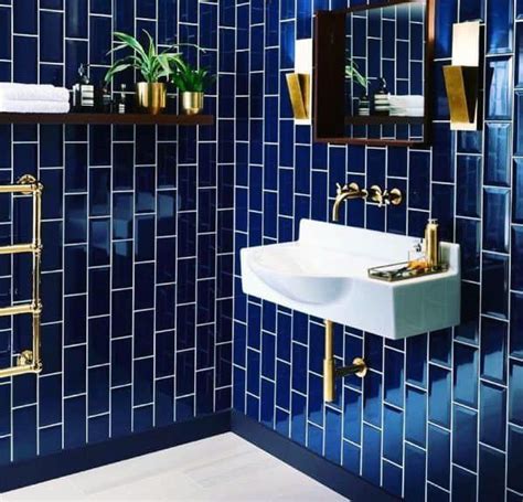 A Blue Tiled Bathroom With Gold Fixtures And Mirrors On The Wall Along