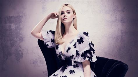 Mary Elle Fanning With Purple And Black Gown Is Sitting On A Black