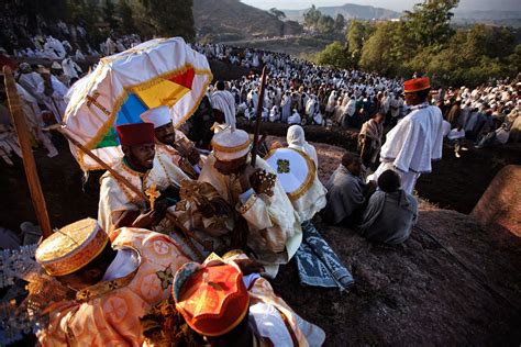 Several People Dressed In White And Orange Sitting On The Ground