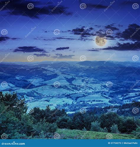 Village On Hillside Meadow With Forest In Mountain At Night Stock Image