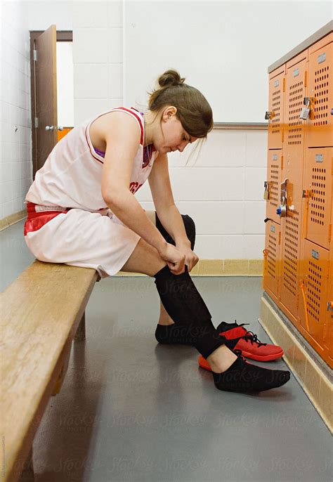 Female Basketball Player Puts Knee Pads On In Locker Room By Stocksy
