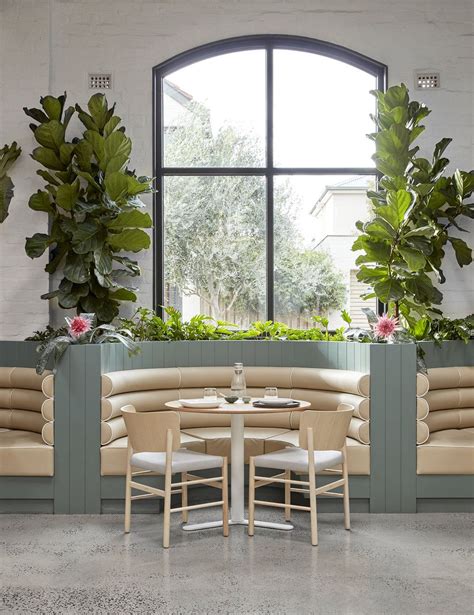 An Indoor Seating Area With Potted Plants On The Wall And Round Tables