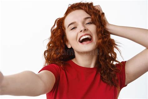 close up portrait of carefree and happy ginger girl touching her curly natural hair and