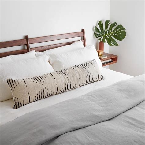 A Bed With White Sheets And Pillows In A Bedroom Next To A Potted Plant