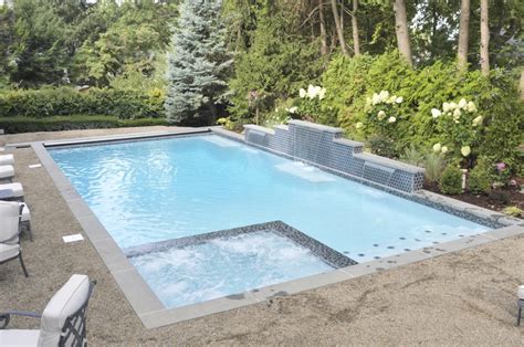 Rectangle pool with spa, mosaic tile, fire element, paver deck, and pool lighting. Gunite Rectangular Pools - Westrock Pools