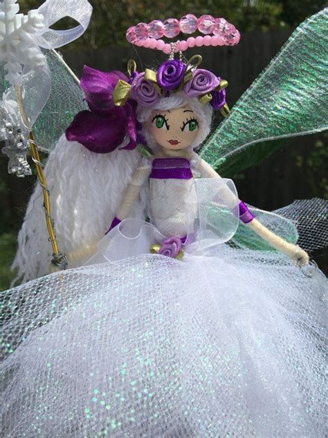 A White And Purple Fairy Doll Sitting On Top Of A Green Netted Table Cloth