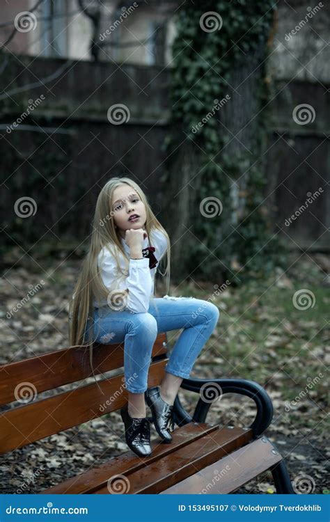 M Dchen In Den Modernen Jeans Sitzen Auf Bank Mode Kleines Kind Mit Dem Langen Blonden Haar