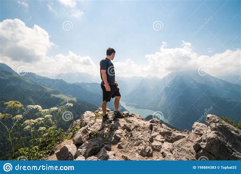Boy Standing On The Top Of A Cliff Watching A Beautiful Mountain