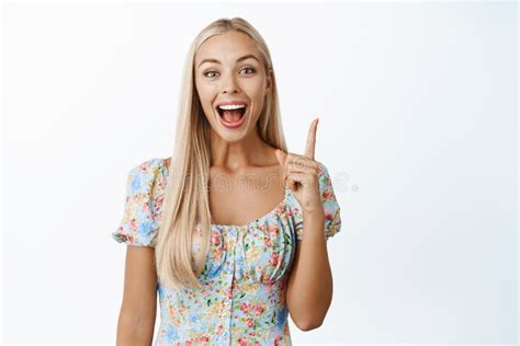 enthusiastic blond girl pointing finger up smiling and showing announcement with happy face