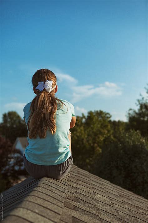 Roof Rear View Of Teen Girl Sitting On The Rooftop Of A House By