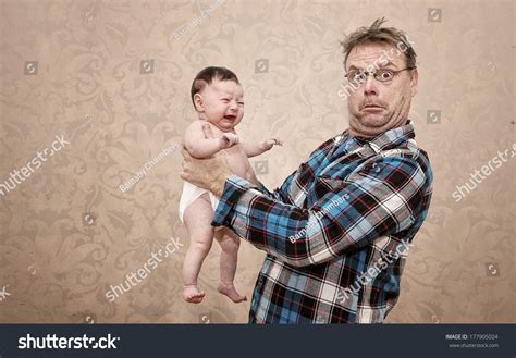 Father Holding His Young Baby With A Surprised And Confused Expression