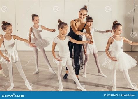 Young Professional Female Ballerina Teaching Girls To Dance Stock Photo