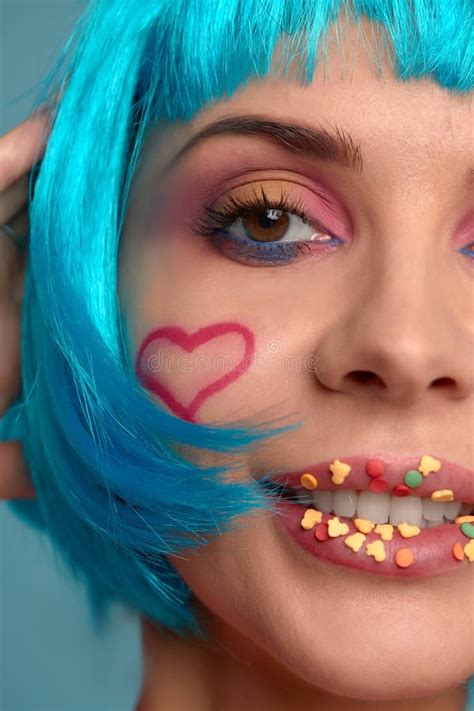 close up of a flirtatious female model on blue background wearing a blue wig pretty glamorous