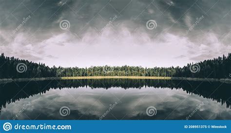 Reflection Of The Cloudy Sky On The Lake Surrounded By Trees Stock