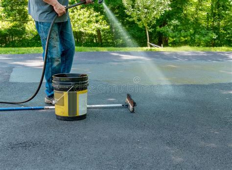 Cracks are inevitable on asphalt driveways. Pouring Asphalt Sealant On Driveway Stock Photo - Image of maintenance, driveway: 119357580