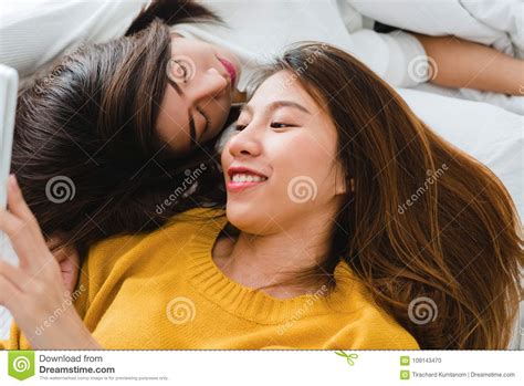 schönes junges asiatisches lesbisches umarmendes und beim im bett zusammen liegen lächelndes
