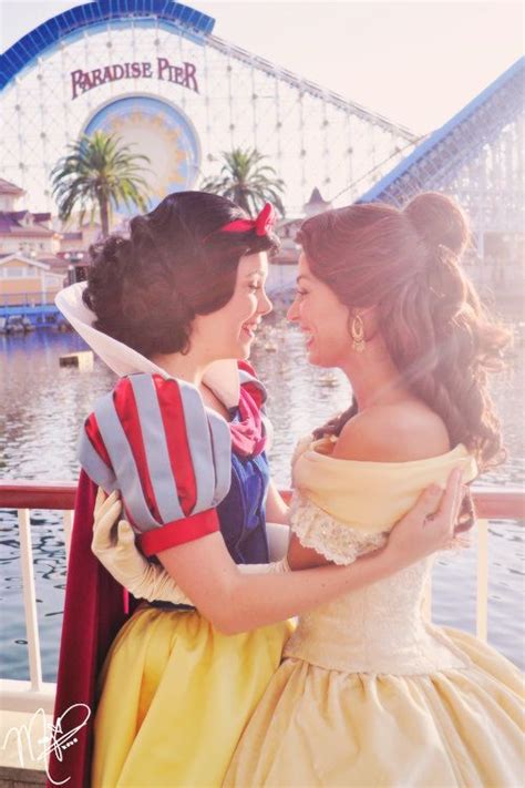 Two Women Dressed As Snow And Princesses Standing Next To Each Other