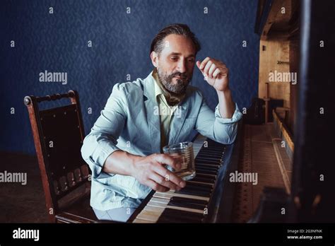 Brutal Man With A Beard 40 Years Old Plays The Old Piano Stock Photo