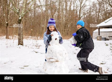 Two Happy Children Build Snowman Together In Winter Stock Photo Alamy
