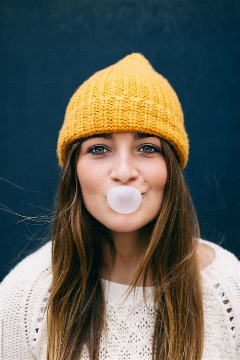 funny portrait of a beautiful 14 years old girl making bubbles out of a bubble gum by stocksy