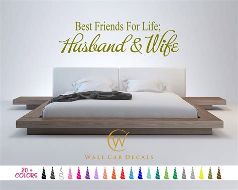 A Bed With White Sheets And Pillows In Front Of A Wall Decal That Says