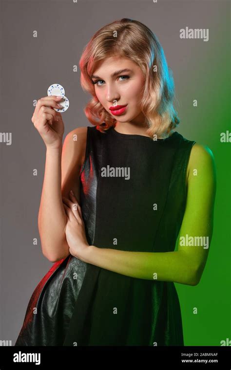 Dazzling Blonde Female With Bright Make Up In Black Stylish Dress Is Holding Two Chips And