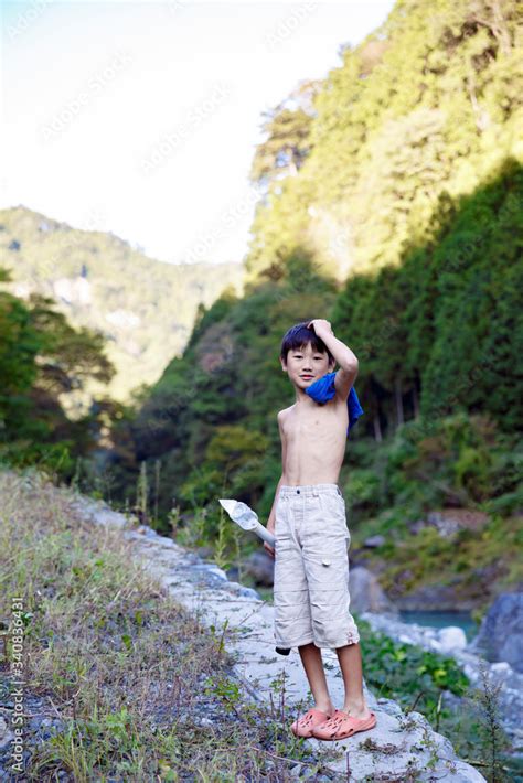 川原で上半身裸の少年 Photos Adobe Stock