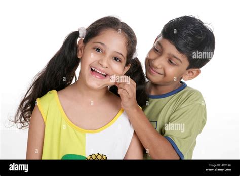 Boy Pinching His Sisters Cheeks And Smiling Stock Photo Alamy