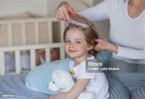 Seorang Ibu Muda Yang Bahagia Menyisir Rambut Putri Kecilnya Yang