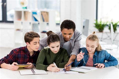Multiethnic Group Of Teenagers Doing Homework Together In Class Stock