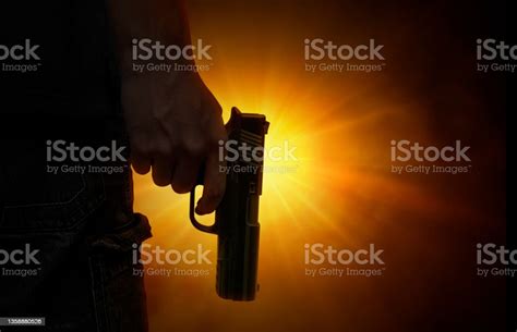 Male Hand Holding Gun On Black Background With Smoke Colored Back