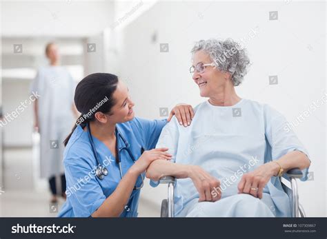 Elderly Patient Looking At A Nurse In Hospital Ward Stock Photo