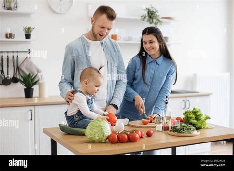 Funny girl in denim outfit holding bell pepper while proud mother