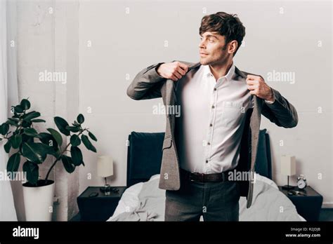 Side View Of Handsome Businessman Putting On Jacket In Bedroom At Home