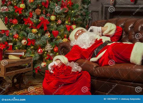 Santa Clause Snoozing In A Decorated Living Room With Sack Full Stock