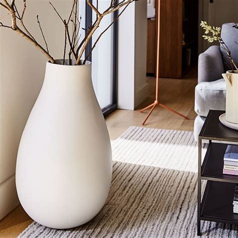 Two White Vases With Branches In Them Sitting On A Rug Next To A Coffee