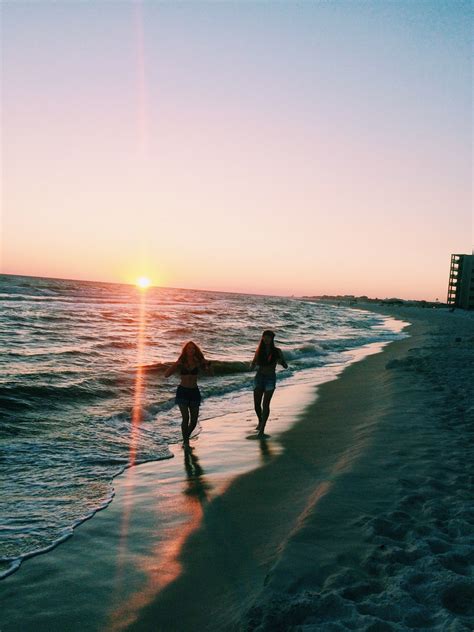 Two Women Walking On The Beach At Sunset