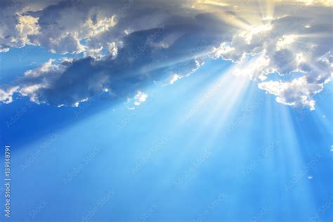 Sun Light Rays Or Beams Bursting From The Clouds On A Blue Sky
