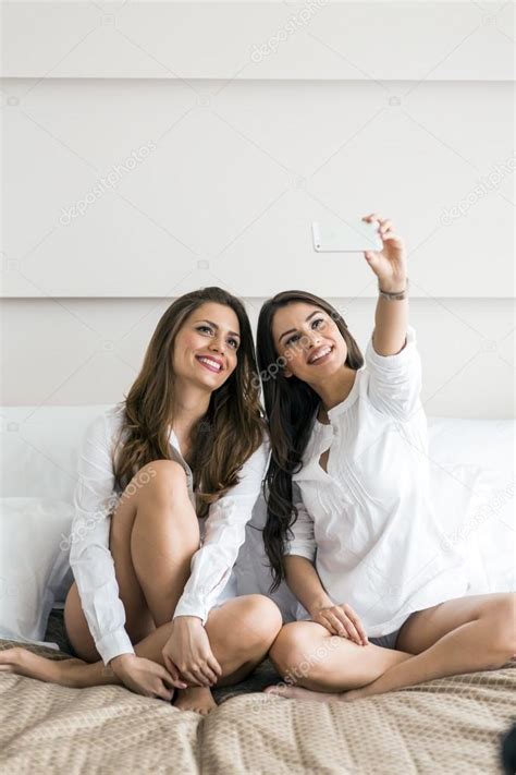 Chicas calientes tumbadas en una cama tomando una foto de sí mismas