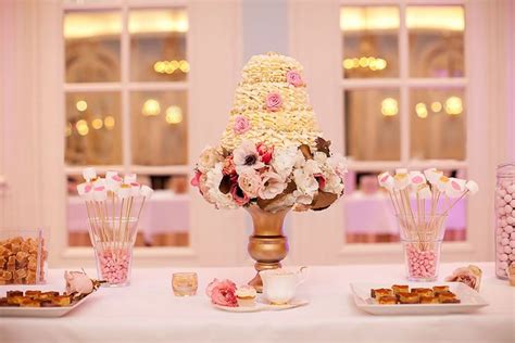 A Table Topped With Lots Of Desserts Next To Tall Vases Filled With Flowers