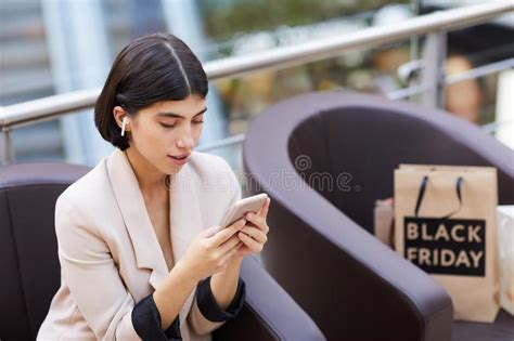 Beautiful Woman Using Smartphone While Relaxing In Shopping Mall Stock