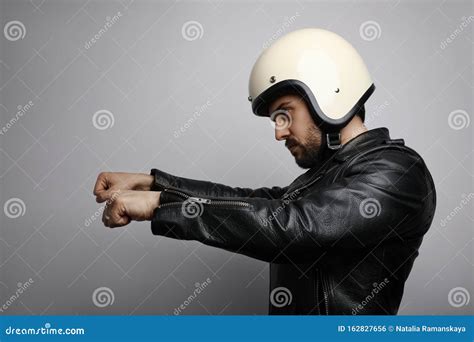 Young Biker Man In A Leather Jacket Pretending To Ride A Motorcycle Isolated On A White