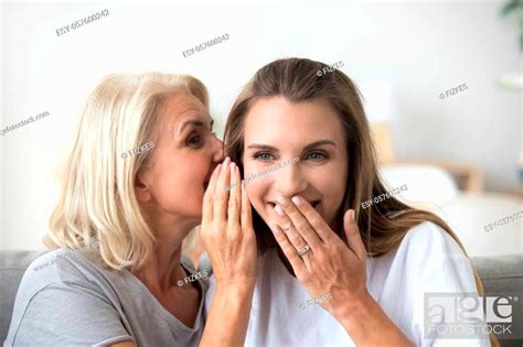excited aged mother whisper in daughter ear sharing secret with her spending time together at