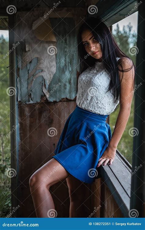 Young Adult Seductive Brunette In Blue Skirt And White Shirt Posing In Rustic House Outdoors