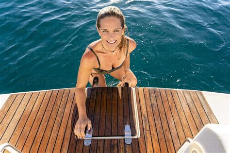 Smiling Woman In Bikini Moving Up On Sailboat Stock Photo