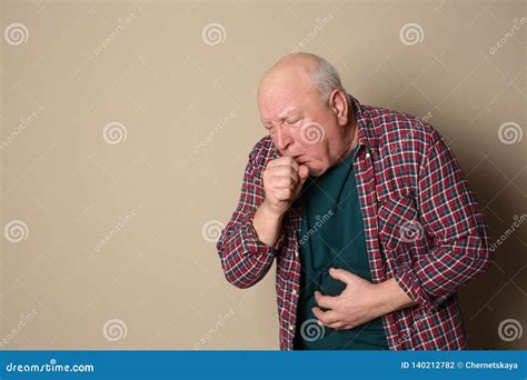 Senior Man Suffering From Cough On Color Background Stock Photo